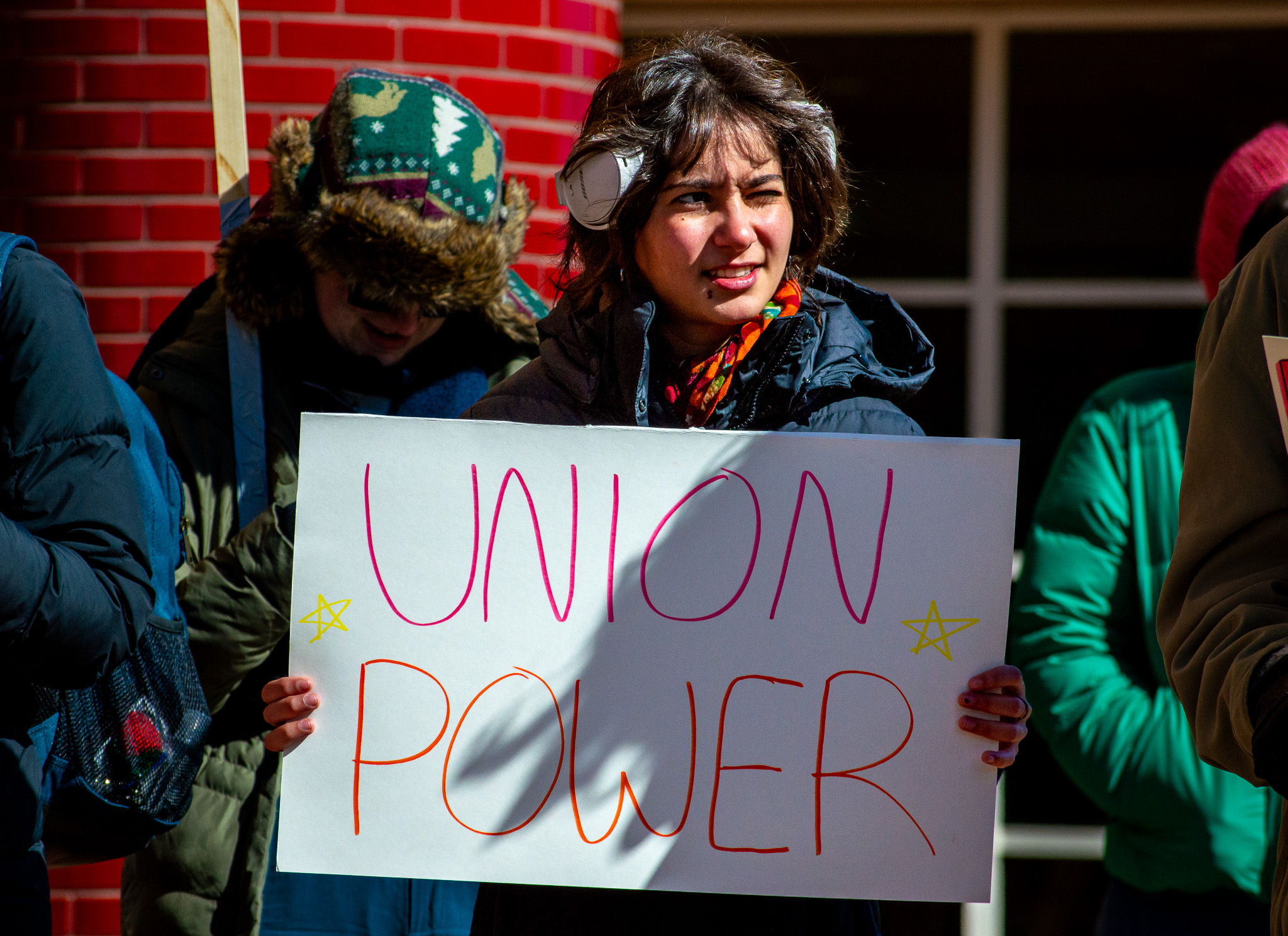 A photograph of a Grinnell student holding a sign that says "Union Power""